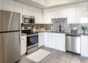 Thumbnail 18 of 30 - A modern kitchen with stainless steel appliances and white cabinets at Saba Pompano Beach, Pompano Beach, 33062