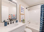 Thumbnail 6 of 16 - A bathroom with a white sink and a white toilet.