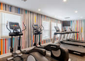 Thumbnail 11 of 16 - A row of treadmills in a gym with striped wallpaper.