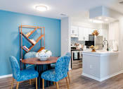 Thumbnail 2 of 16 - A dining room with a round table and blue chairs.