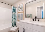 Thumbnail 7 of 16 - A white bathroom with a toilet, sink, and shower.