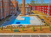 Thumbnail 3 of 33 - A large swimming pool surrounded by red brick buildings.