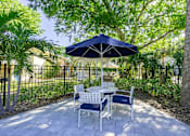 Thumbnail 16 of 20 - A patio with a table and chairs under an umbrella.