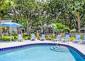 Thumbnail 14 of 20 - A pool surrounded by trees and chairs.