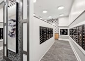Thumbnail 19 of 24 - A hallway with a series of lockers on the right and a framed picture on the left.