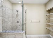Thumbnail 21 of 39 - A walk-in shower with a glass door and a bench seat.