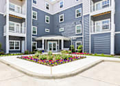 Thumbnail 28 of 30 - A large building with a flower bed in front.