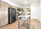 Thumbnail 1 of 30 - A kitchen with a black fridge and a white table.