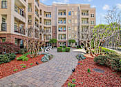 Thumbnail 25 of 39 - A brick walkway leads to a courtyard with a fence and trees.