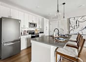 Thumbnail 2 of 24 - A modern kitchen with a large island and a refrigerator.