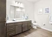 Thumbnail 7 of 30 - A bathroom with a white sink and a white toilet.