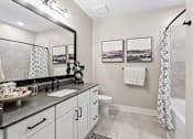 Thumbnail 8 of 24 - A bathroom with a large mirror, a sink, a toilet, and a shower.