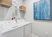 Thumbnail 9 of 24 - A laundry room with a washer and dryer and a painting on the wall.