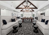 Thumbnail 11 of 24 - A modern living room with a large wooden table and two white couches.