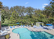Thumbnail 24 of 33 - a swimming pool with chairs and umbrellas next to a house
