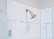 Thumbnail 38 of 54 - a white tiled bathroom with a shower and a soap dispenser