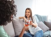 Thumbnail 13 of 28 - two women sitting on a couch drinking wine