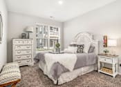 Thumbnail 6 of 51 - A bedroom with a bed, nightstand, and chair.