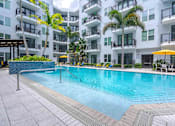 Thumbnail 16 of 22 - A swimming pool in front of a white building with balconies.