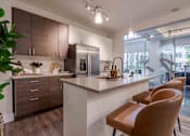 Thumbnail 6 of 22 - 2-Bedroom Apartments in Tampa, FL - Society Westshore - Kitchen with Wood Plank Style Flooring, Large Island with Seating, Pendant Lights, Quartz Countertops, Stainless Steel Appliances, and Flat-Panel Cabinetry.