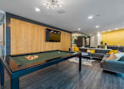 Thumbnail 14 of 22 - A pool table is in the middle of a room with a couch and a TV mounted on the wall.