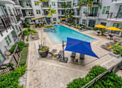Thumbnail 18 of 22 - A blue umbrella is on the patio of a pool.