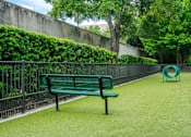 Thumbnail 19 of 22 - A green bench sits on a green lawn next to a green playground equipment.