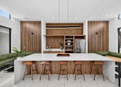 Thumbnail 25 of 35 - A modern kitchen with a bar area and wooden stools.