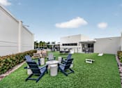 Thumbnail 21 of 35 - A white building with a green lawn in front and blue chairs.