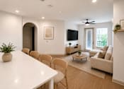 Thumbnail 33 of 40 - A living room with a white table and chairs.