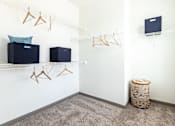 Thumbnail 21 of 30 - A room with a white wall and a shelf with clothes hangers and a laptop on it.