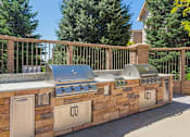 Thumbnail 22 of 37 - A stone and wood outdoor kitchen with a grill and sink.