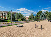 Thumbnail 24 of 37 - A sandy playground area with a slide and a bench.