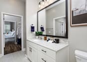 Thumbnail 23 of 24 - A bathroom with a white vanity and a large mirror.