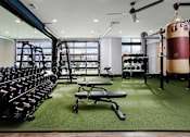 Thumbnail 13 of 24 - A gym with a green floor and a variety of equipment.
