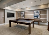 Thumbnail 9 of 24 - A pool table in a room with a television and a painting on the wall.