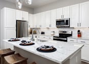Thumbnail 16 of 24 - A kitchen with white cabinets and a marble countertop.