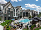 Thumbnail 24 of 26 - A large apartment complex with a pool and a gated fence.