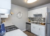 Thumbnail 23 of 44 - an open kitchen with a large clock on the wall and a stove and sink