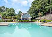 Thumbnail 11 of 18 - A swimming pool surrounded by trees and a house.