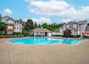 Thumbnail 25 of 29 - A swimming pool surrounded by a concrete patio and residential buildings.