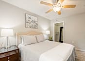 Thumbnail 7 of 36 - A bedroom with a bed, nightstand, and a ceiling fan.