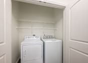 Thumbnail 13 of 35 - A white washer and dryer in a small laundry room.