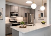 Thumbnail 10 of 35 - A modern kitchen with a white countertop and stainless steel appliances.