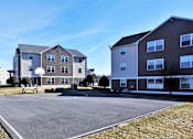 Thumbnail 15 of 15 - A parking lot in front of apartment buildings.