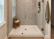 Thumbnail 39 of 56 - A bathroom with a white shower stall and a small wooden table with a plant on it.