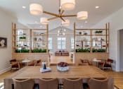 Thumbnail 2 of 56 - A large wooden dining table surrounded by chairs with a long wooden shelf with plants on it.