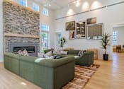 Thumbnail 4 of 56 - A living room with a stone fireplace and green couches.