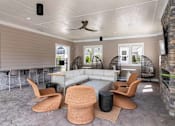 Thumbnail 55 of 56 - A modern outdoor living space with a white ceiling fan and a stone wall.
