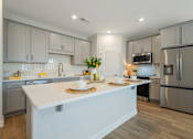 Thumbnail 16 of 56 - A modern kitchen with a white island and stainless steel appliances.